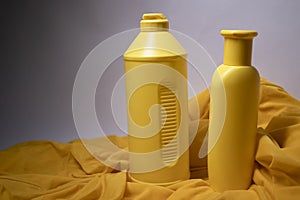 Composition of two yellow shampoo bottles with no label in a silk yellow fabric.body care and beauty concept. Copy space