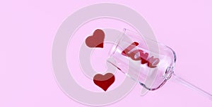 Composition for Valentine\'s Day with red hearts and word LOVE in wineglass on the pink background. Top view. Copy space.