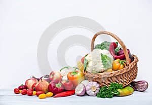 Composition with variety of fresh organic vegetables in wicker basket isolated on white