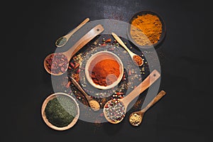 Composition with variety of spices and herbs on black background top view. Cooking ingredients and condiments concept