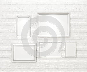 Composition of white blank picture frames on white brick wall with spotlights