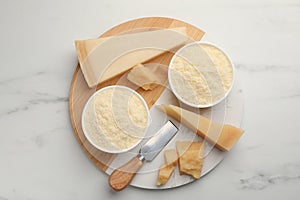 Composition with whole and grated parmesan cheese on white marble table, top view