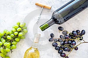 Composition with wine bottles. Red and white wine bottles, bunch of grapes, corkscrew on grey background top view space