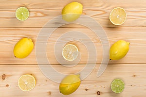 Composition on a wooden light background of lobules and whole lemons