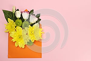 Composition of yellow, green Santini chrysanthemums and roses in an envelope on a pink background