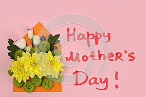 Composition of yellow, green Santini chrysanthemums and roses in an envelope on a pink background and the inscription Happy mother