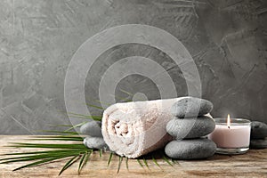 Composition with zen stones, towel and candle on table against grey background