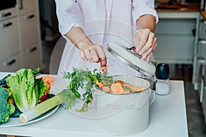 Compost the kitchen waste, recycling at home. Woman putting vegetables cutted leftovers into the garbage, compost bin on