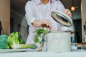 Compost the kitchen waste, recycling at home. Woman putting vegetables cutted leftovers into the garbage, compost bin on