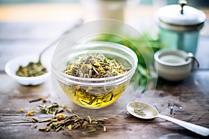 composted green tea in a transparent cup with loose tea leaves around