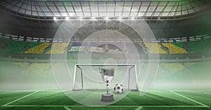 Compostion of cup and football over stadium and goal photo