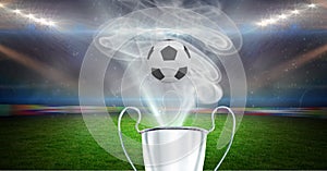 Compostion of cup and football over stadium and white smoke