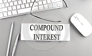 COMPOUND INTEREST text on paper with keyboard on grey background