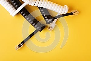 Compressed black and white spiral phone cord with connectors on yellow background