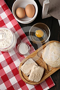 Compressed yeast, salt, flour, eggs and dough on wooden table, flat lay