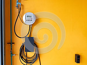 Compressor digital inflator kit with rubber pipe hanging on yellow wall