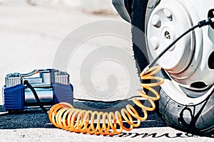 The compressor electric pump inflates the flat tire of the car. Roadside assistance and troubleshooting on the way