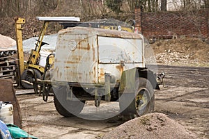 A rusty old mobile industrial compressor on a construction site.