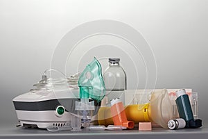 Compressor and portable inhalers, replaceable dispenser, ampoules and baby mask, on grey