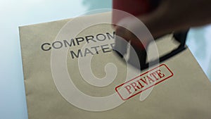 Compromising material private, hand stamping seal on folder with documents