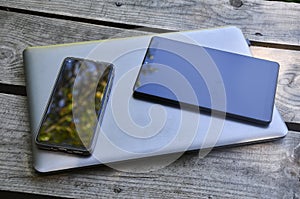 Computadora portÃÂ¡til gris con telÃÂ©fono mÃÂ³vil al lado y tablet sobre una mesa de madera photo