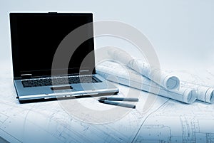 Computer and architectural plans in blue tint
