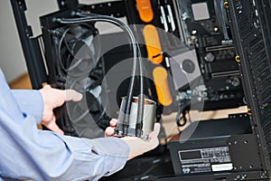 Computer assembling service. Serviceman installing liquid cooling system on processor