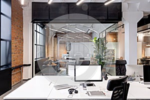 Computer with blank screen on the working place in the modern loft office