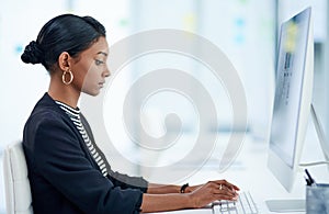 Computer, business and Indian woman typing email, report or writing information in office. Serious, pc and professional