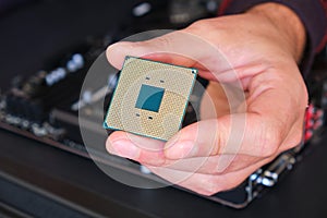 Computer chip CPU held by a man with his fingers - close up of the pins grid