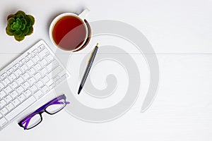 Computer, coffee, glasses, pen and cactus on white wooden table