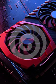 Computer game graphics card, videocard with two coolers on circuit board ,motherboard background. Close-up. With red-blue lighting