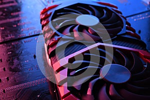 Computer game graphics card, videocard with two coolers on circuit board ,motherboard background. Close-up. With red-blue lighting