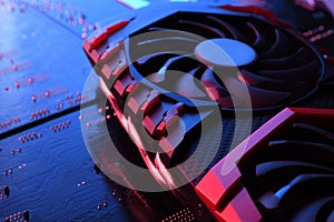 Computer game graphics card, videocard with two coolers on circuit board ,motherboard background. Close-up. With red-blue lighting