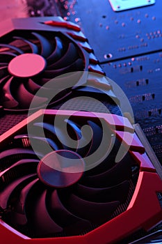 Computer game graphics card, videocard with two coolers on circuit board ,motherboard background. Close-up. With red-blue lighting