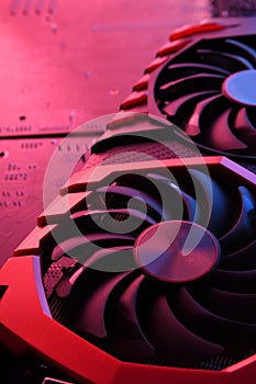 Computer game graphics card, videocard with two coolers on circuit board ,motherboard background. Close-up. With red-blue lighting