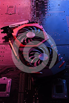 Computer game graphics card, videocard with two coolers on circuit board ,motherboard background. Close-up. With red-blue lighting