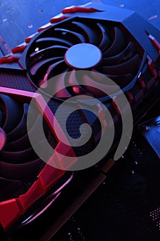 Computer game graphics card, videocard with two coolers on circuit board ,motherboard background. Close-up. With red-blue lighting