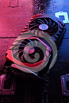 Computer game graphics card, videocard with two coolers on circuit board ,motherboard background. Close-up. With red-blue lighting