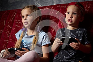 Computer games: a boy and a girl play a game console in the dark and hold gamepads in their hands.