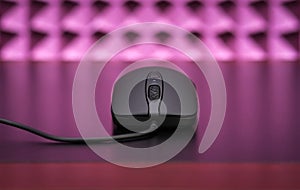 Computer gaming mouse on a table on a pink studio background