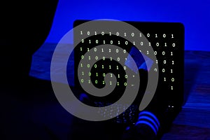 Hacker with Credit Card Stealing Data from A Laptop in The Dark photo