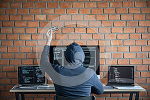 Computer hacker or cyber attack concept, Dangerous hooded hacker using multiple computers typing bad data into online system the