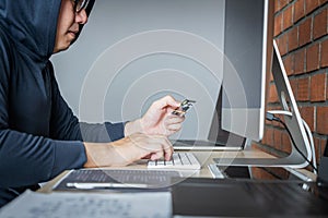 Computer hacker or cyber attack concept, Dangerous hooded hacker using multiple computers typing bad data into online system the