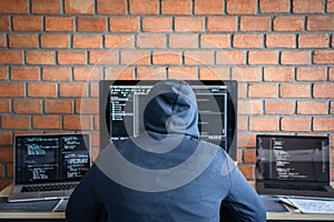 Computer hacker or cyber attack concept, Dangerous hooded hacker using multiple computers typing bad data into online system the