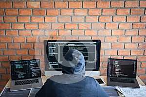 Computer hacker or cyber attack concept, Dangerous hooded hacker using multiple computers typing bad data into online system the