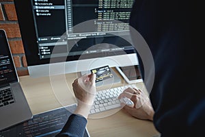 Computer hacker or cyber attack concept, Dangerous hooded hacker using multiple computers typing bad data into online system the