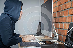 Computer hacker or cyber attack concept, Dangerous hooded hacker using multiple computers typing bad data into online system the