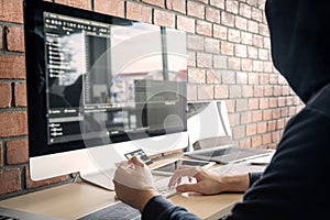 Computer hacker or cyber attack concept, Dangerous hooded hacker using multiple computers typing bad data into online system the