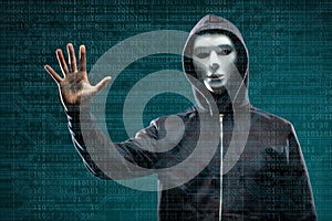 Computer hacker in mask and hoodie over abstract binary background. Obscured dark face. Data thief, internet fraud